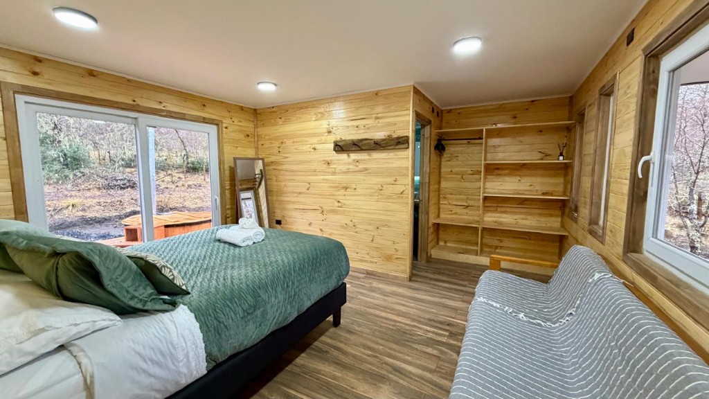 Dormitorio principal de Refugio Kürü con cama, sofá cama y clóset de madera