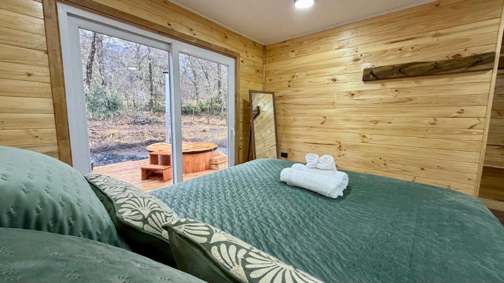 Dormitorio principal de Refugio Kürü con vista a la tinaja y al bosque desde la cama